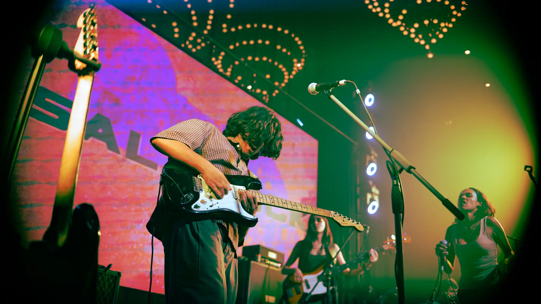 Guitarist on a festival stage in front of the logo wall