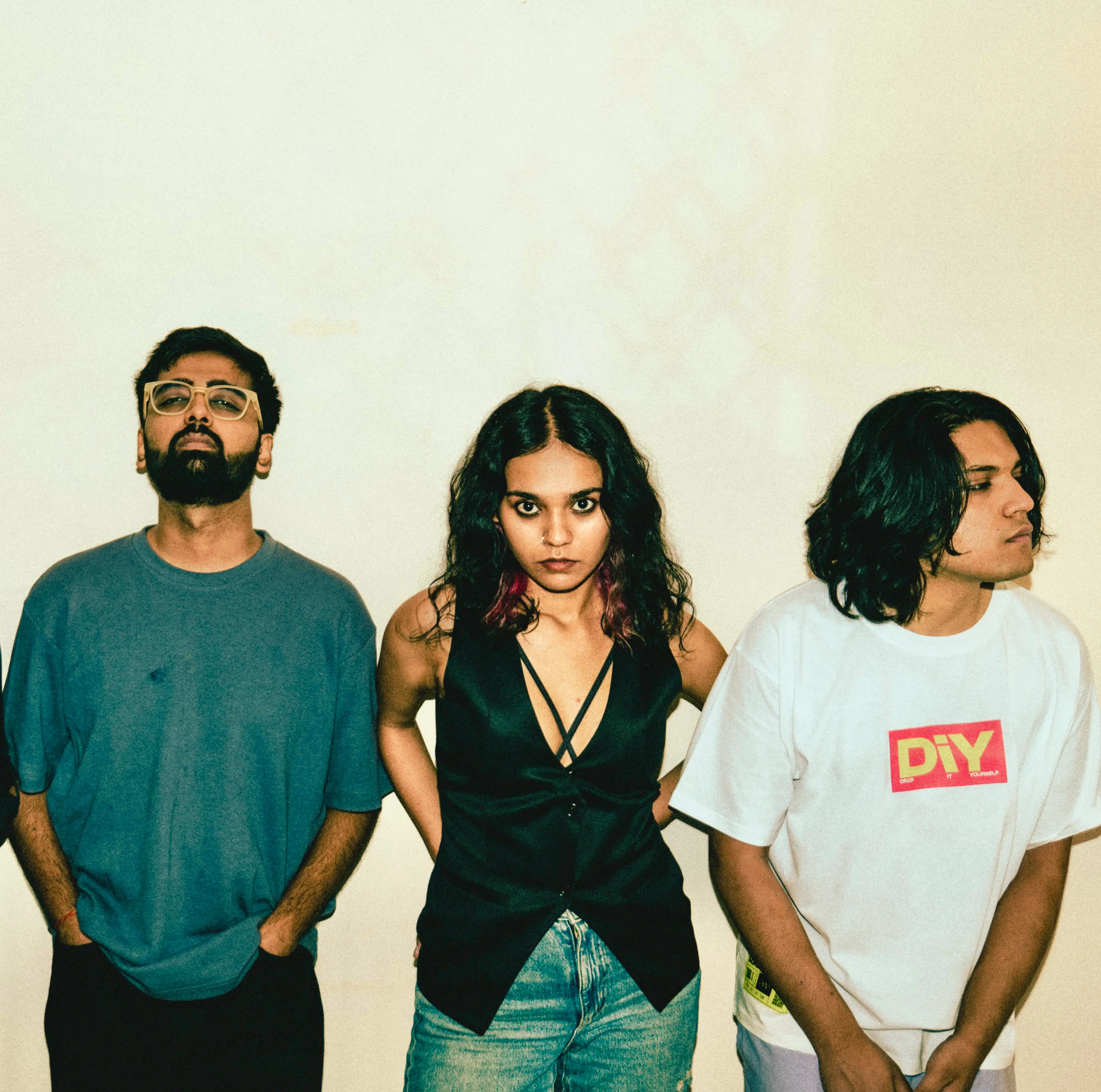 The band against a white wall, staring down the lens
